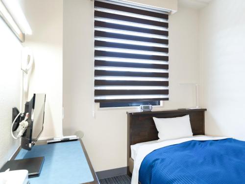 a bedroom with a bed and a desk and a window at ホテルマリンピア in Enokizu