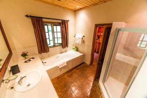 リロングウェにあるKumbali Country Lodgeの浴槽、洗面台、シャワーを備えたバスルーム