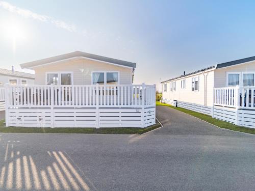 a white house with a white fence in front of it at 3 bedroom Lodge at Pevensey Bay in Pevensey