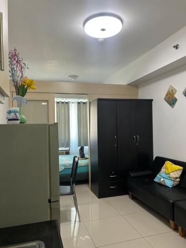 a living room with a black couch and a bedroom at Sea Residences Ann in Manila