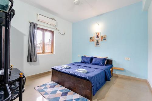 a bedroom with a bed with blue sheets and a window at ILLY's NEST in Siolim