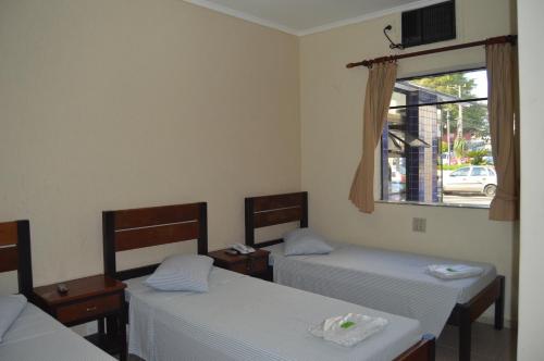 サンパウロにあるHotel Aeroporto de Congonhasのベッド3台と窓が備わる客室です。