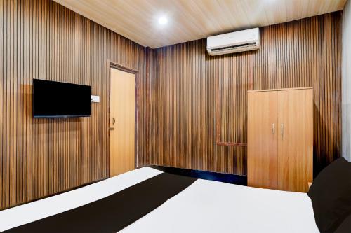 1 dormitorio con 1 cama, TV y pared en Hotel O Nepali Mandir Bus Terminal Formerly Hotel Aaghnya, en Guwahati