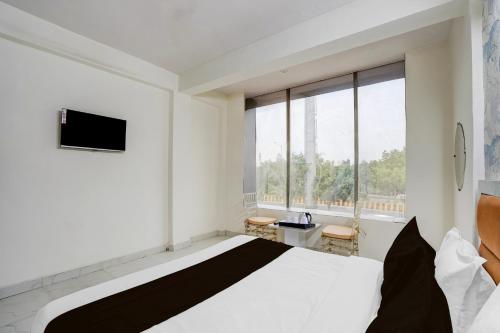 Un dormitorio con una cama y una ventana grande. en Super Hotel O Sector 51 Metro Station Formerly Shubham Residency, en Indirapuram