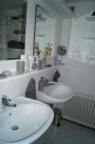 ein Badezimmer mit zwei weißen Waschbecken und einem Spiegel in der Unterkunft Ferienwohnung-im-Speicher in Meldorf
