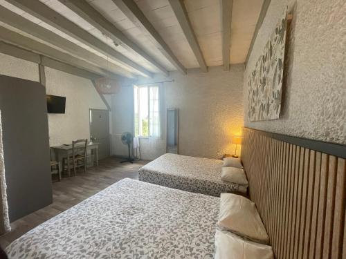 a bedroom with two beds and a table in a room at Hôtel et RESTAURANT traditionnel L' Escalandes in Lesperon