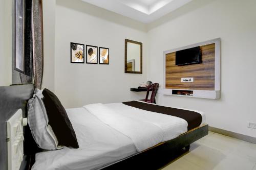 シルディにあるHotel O Sai Teerth Theme Park Formerly Sai Dhanlaxmiのベッドと壁にテレビが掛かった寝室
