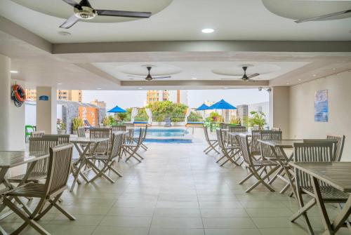 a dining room with tables and chairs and a pool at Howard Johnson by Wyndham Barranquilla Versalles in Barranquilla