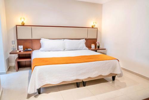 a bedroom with a large bed with an orange blanket at Howard Johnson by Wyndham Barranquilla Versalles in Barranquilla