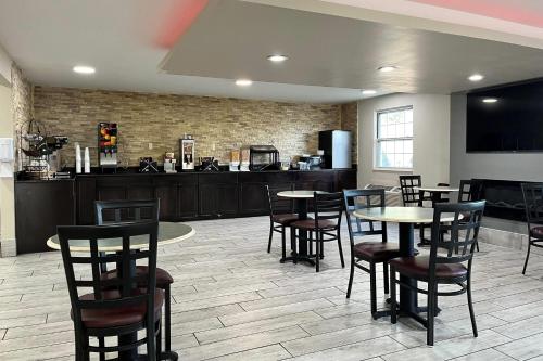 a restaurant with tables and chairs and a kitchen at Baymont by Wyndham Indianapolis Airport Lynhurst in Indianapolis