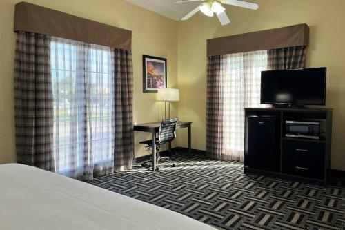 a hotel room with a bed and a desk with a television at Baymont by Wyndham Indianapolis Airport Lynhurst in Indianapolis