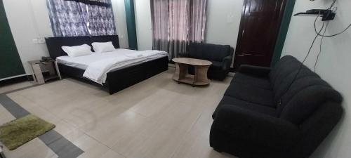 Un dormitorio con una cama, un sofá y una silla. en Townhouse Howell Crossway Shillong (Formerly Laban Guest House, en Shillong