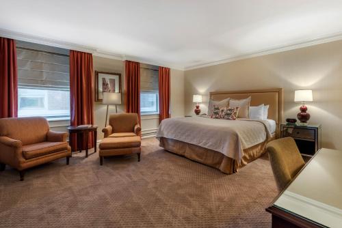 a large bedroom with a bed and two chairs at Omni William Penn Hotel in Pittsburgh