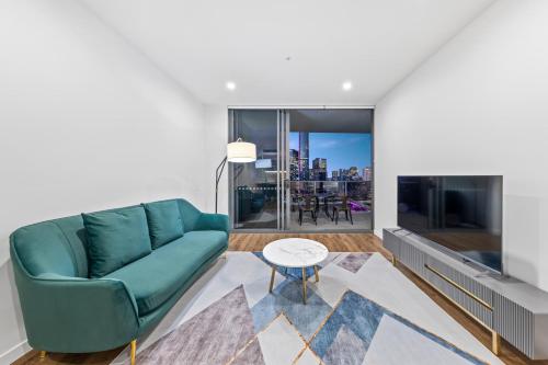 a living room with a green couch and a large tv at Lucid Apartments by CLLIX in Brisbane