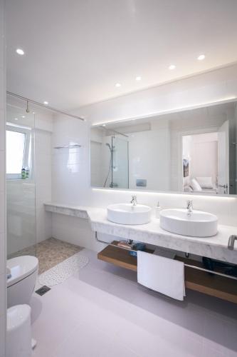 a white bathroom with two sinks and a toilet at White Villas in Dhounaíika