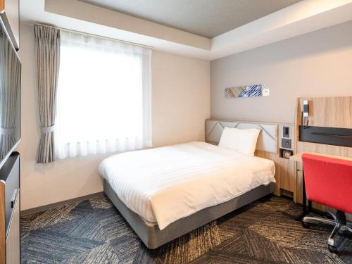 a hotel room with a bed and a red chair at Comfort Hotel Nagoya Kanayama in Nagoya