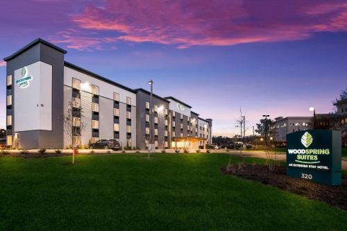 a building with a sign in front of a grass field at WoodSpring Suites Knoxville West in Knoxville