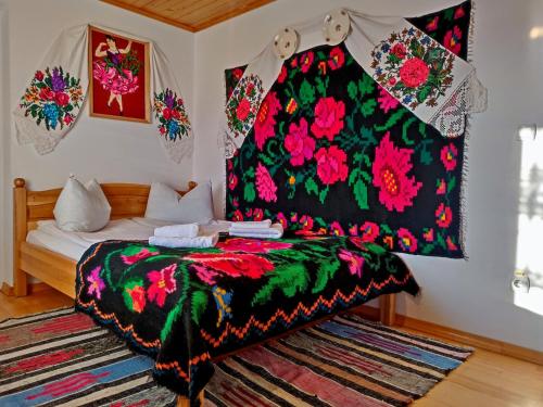 a bedroom with a bed with a colorful blanket at Pensiunea Potcovaru in Vişeu de Sus