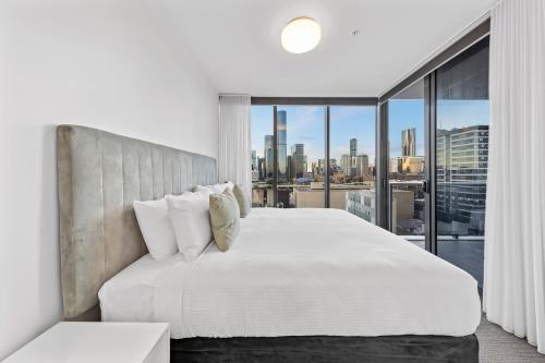 a bedroom with a white bed and a large window at Lucid Apartments by CLLIX in Brisbane
