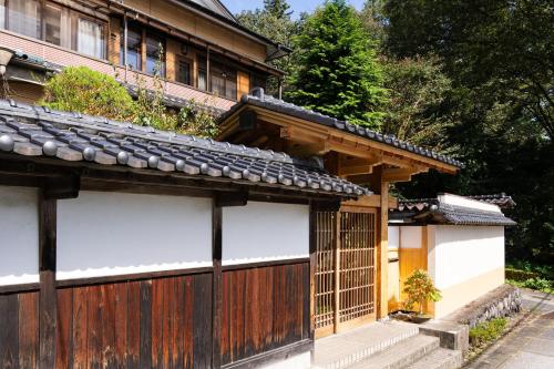 an old house with a wooden fence next to it at 春日光 HaruNikko Guesthouse - Traditional Japanese Guesthouse with Japanese Garden in Nikko