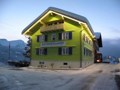 a green building with a sign on the side of it at Katharinahof Ferienpension in Sibratsgfäll
