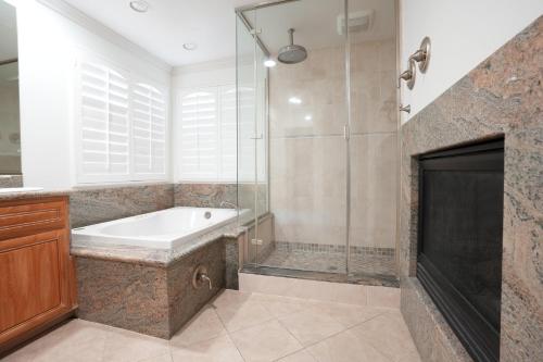 a bathroom with a tub and a shower and a fireplace at Destination #16 in Anaheim