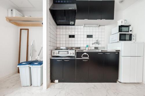 札幌市にあるYELLOWのキッチン(黒いキャビネット、白い電化製品付)