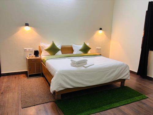 a bedroom with a large bed with green pillows at Jim Corbett Guest House in Jhirna