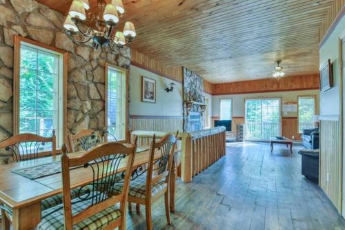 Una sala de estar con una mesa y una pared de piedra. en Spa & Lakefront - Chalet Huard, en Saint-Faustin