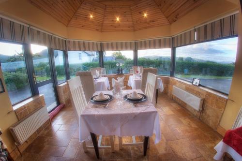 a dining room with tables and chairs and large windows at Walkers Nest in Carlingford