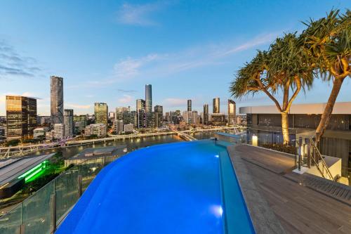 a swimming pool on the roof of a building with a city skyline at Lucid Apartments by CLLIX in Brisbane