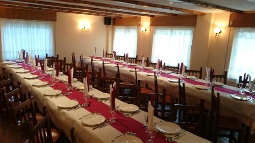 uma fila de mesas num salão de banquetes com guardanapos vermelhos em Casa Poy em Becerreá