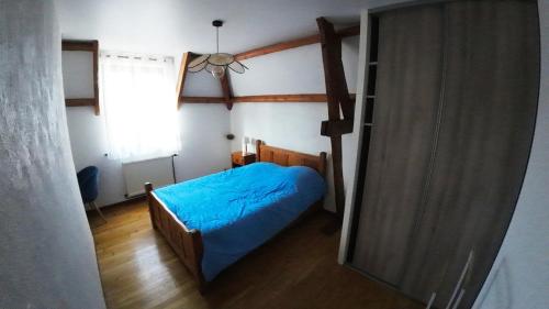 ein kleines Schlafzimmer mit einem blauen Bett und einem Fenster in der Unterkunft Maison de Campagne à Levergies 