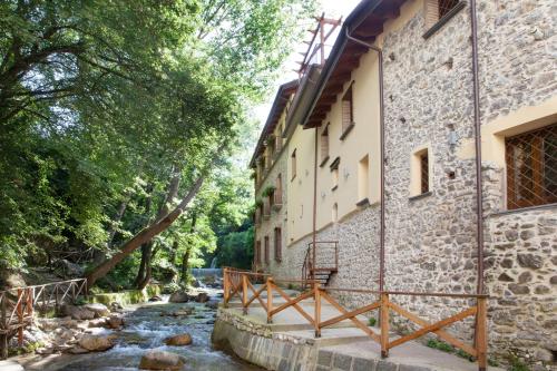a river next to a building with a bridge at Historic Boutique Hotel Maccarunera in Campagna