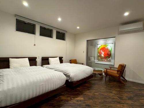 ein Schlafzimmer mit zwei Betten und einem Gemälde an der Wand in der Unterkunft Comlien Villa Resort in Tateyama