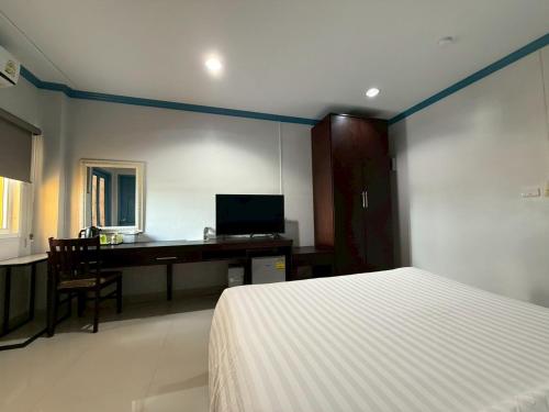 a bedroom with a bed and a desk with a television at Garden Hill Hotel in Trang