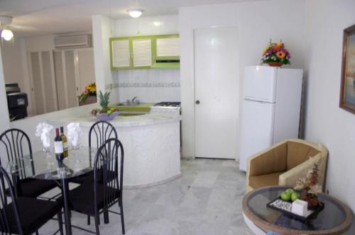 a kitchen with a refrigerator and a table and chairs at Hotel Suites Jazmín Acapulco in Acapulco