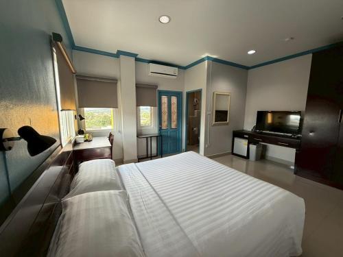 a bedroom with a large white bed and a piano at Garden Hill Hotel in Trang
