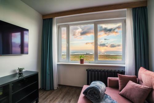 Una sala de estar con un sofá y una ventana grande. en Lakeview stay, stunning sunrises, en Liepāja