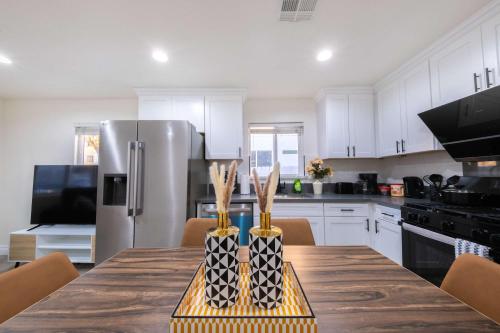 a kitchen with a table with a stainless steel refrigerator at Modern Luxe Ensuite by USC Shared Living in Los Angeles