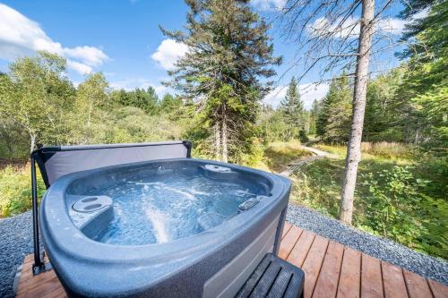 a hot tub sitting on a deck in the woods at Spa & River view - Le Conteneur Cache in Saint-Just-de-Bretenières