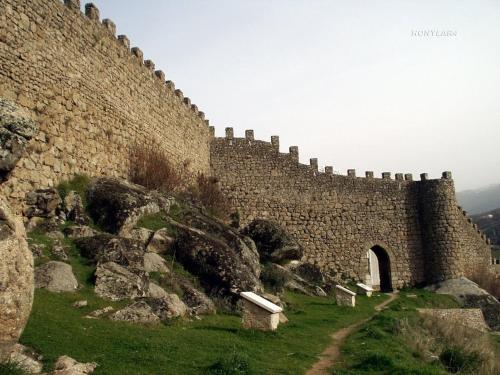 a large stone wall with a path next to it at La Covatilla III in La Hoya