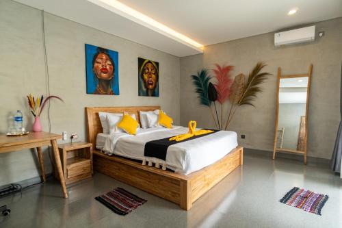 a bedroom with a large bed and paintings on the wall at Villa Alam Kita in Ubud