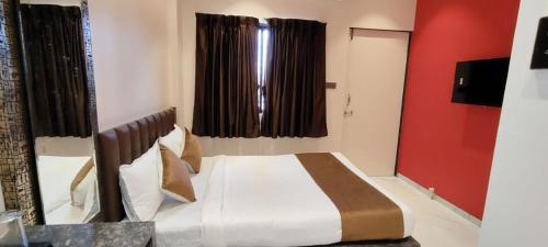 een slaapkamer met een bed en een rode muur bij Eco Wind in Lonavala