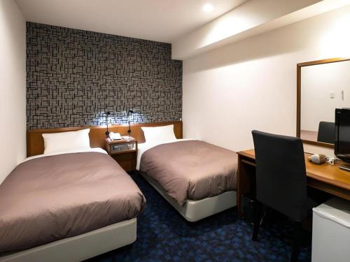 a hotel room with two beds and a desk and a computer at Green Hill Hotel Urban in Kobe
