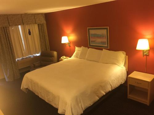 1 dormitorio con 1 cama blanca grande y 1 silla en Americas Best Value Inn - Garden City, en Garden City
