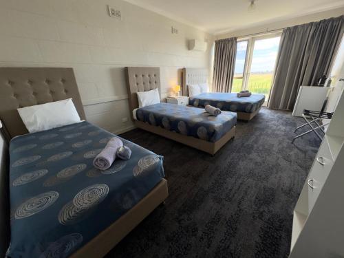 a hotel room with two beds and a window at Tailem Bend Riverside Hotel in Tailem Bend