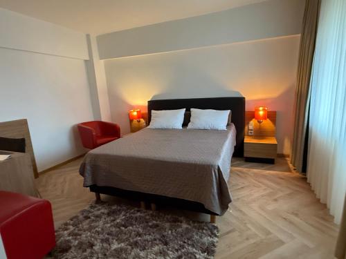 クラヨーヴァにあるCity Centre Craiovaのベッドと赤い椅子のある寝室