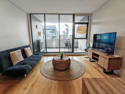 a living room with a couch and a tv at 2BR apt close to MQ shopping centre and university in Sydney