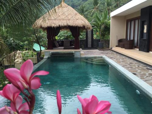 a pool at a villa with pink flowers in the foreground at Nipah Villas in Senggigi 